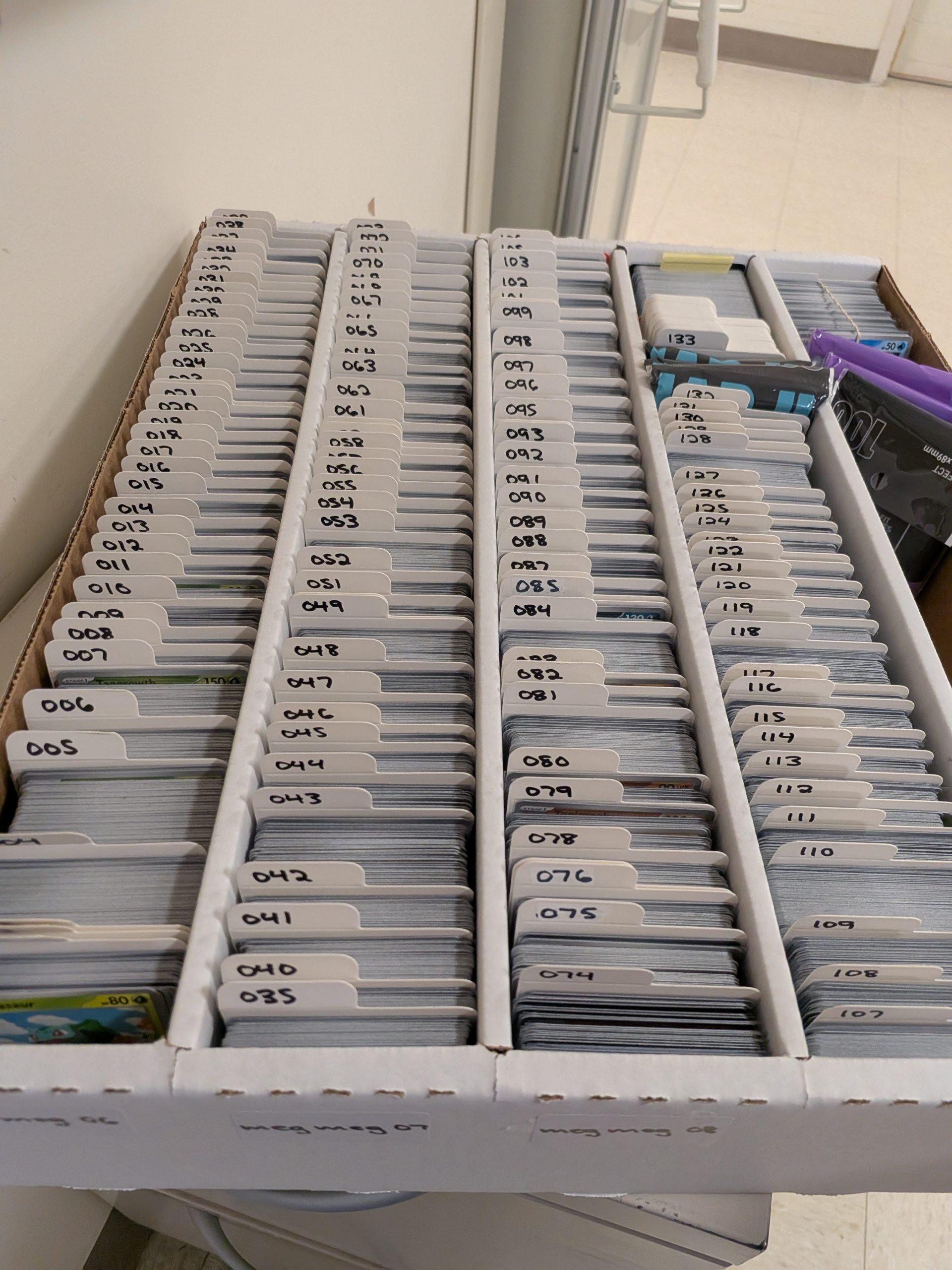 Pictured is a five-row card storage box with four of the rows filled with cards, sorted by number within the set.